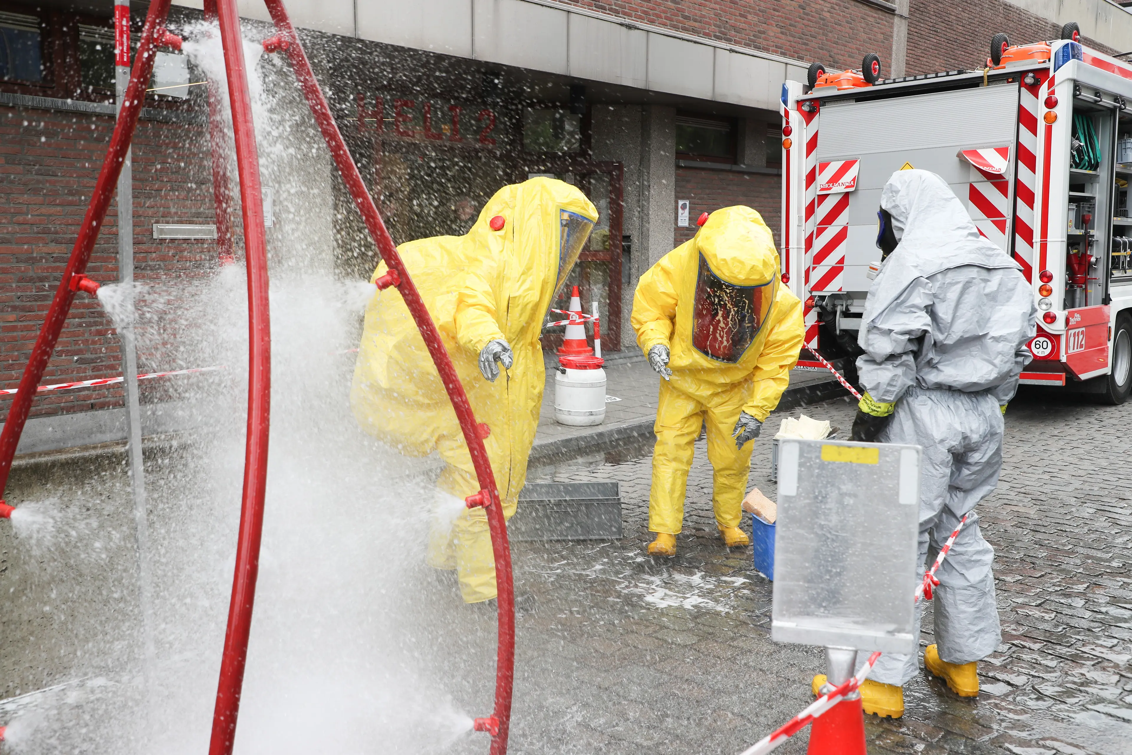 Three firefighters in HAZMAT gear and a mobile decontamination shower