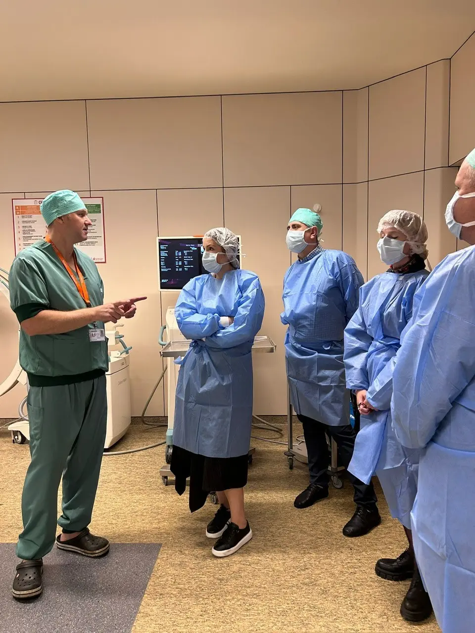 Delegation members in protective clothing listen to a doctor at the hospital